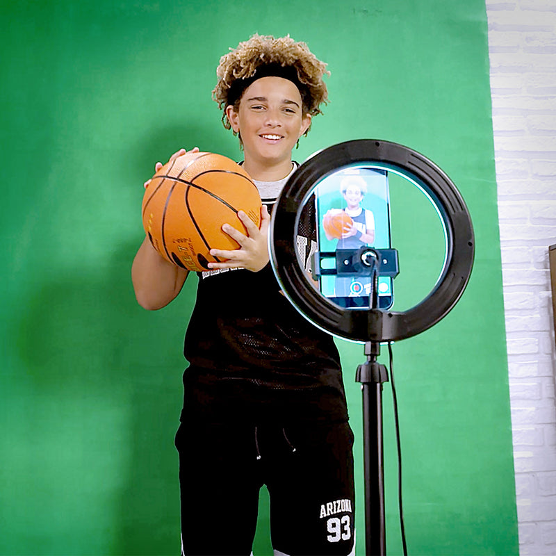 a boy using a green screen and ring light to record a video on a smart phone