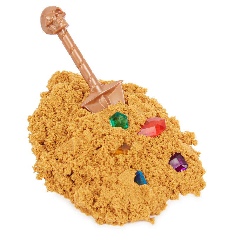 a close up of rare gold kinetic sand with gems and a small spade